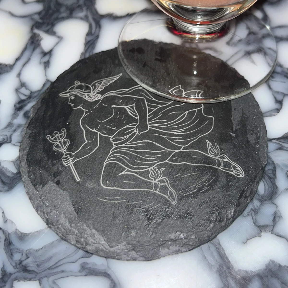 Posavasos oscuro de borde irregular con ilustración de Hermes bajo una copa